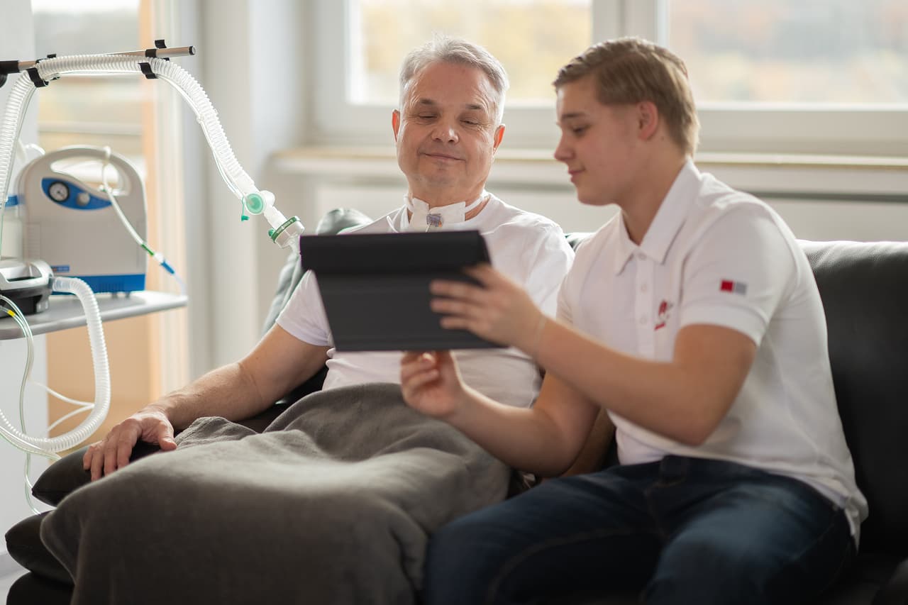 Patiententransport mit Pflegekräften vor Klinikgebäude.